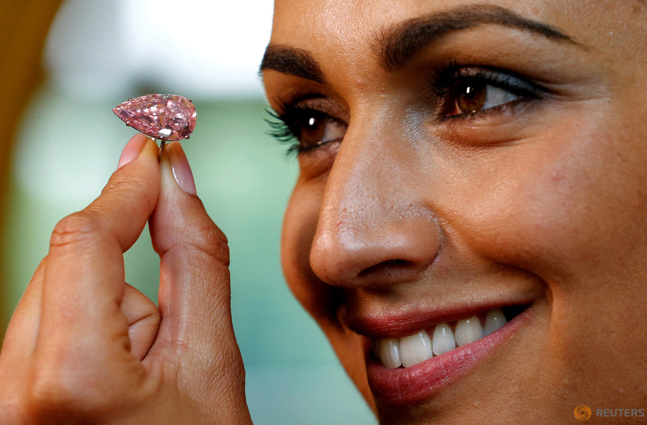 A model poses with the "Unique Pink", a 15.38 carats vivid pink diamond, at Sotheby's auction house in Geneva, Switzerland May 9, 2016. 