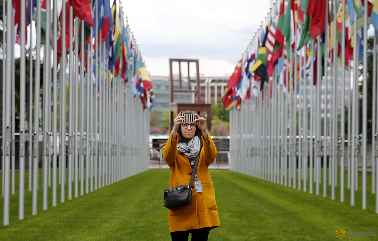 A staff takes a selfie in the flags alley at the European headquarters of the United Nations in Geneva, Switzerland, April 26, 2016. 